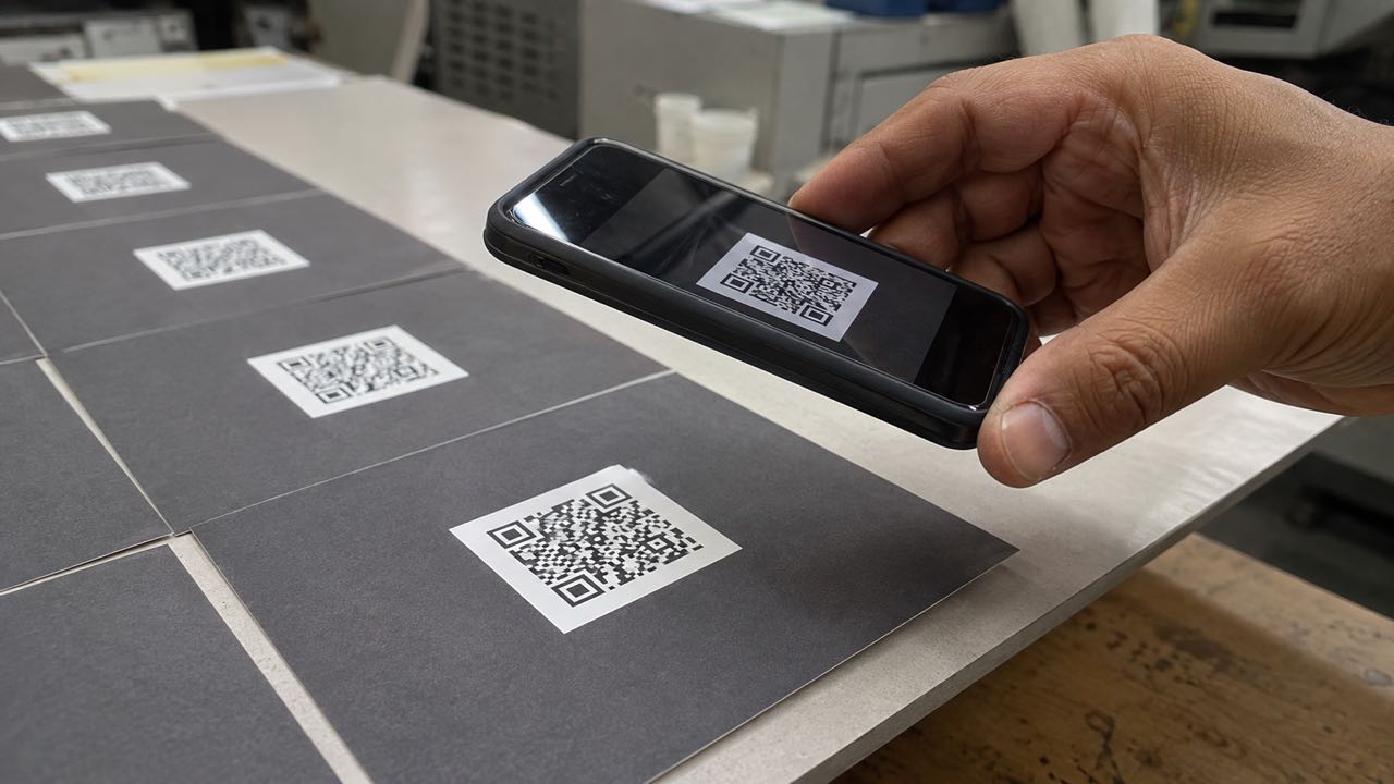 Teléfono escaneando el QR de una tarjeta impresa durante una prueba de calidad