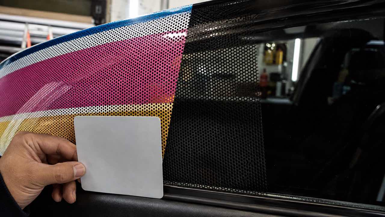 Detalle de los orificios de una película microperforada sobre vidrio automotor